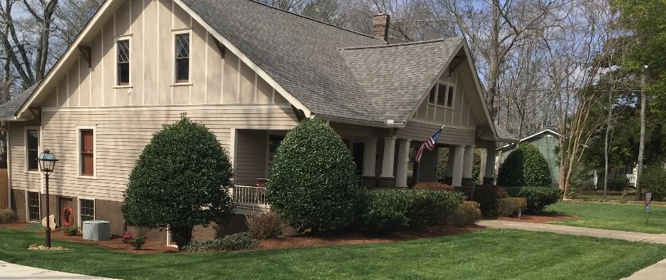 Neat and lush shrubs on a house in Roswell, GA, beside a lawn.